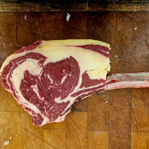 Raw tomahawk steak on a wooden cutting board