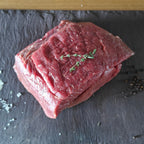 Irish Moiled roast beef joint on a slate board with a wooden background