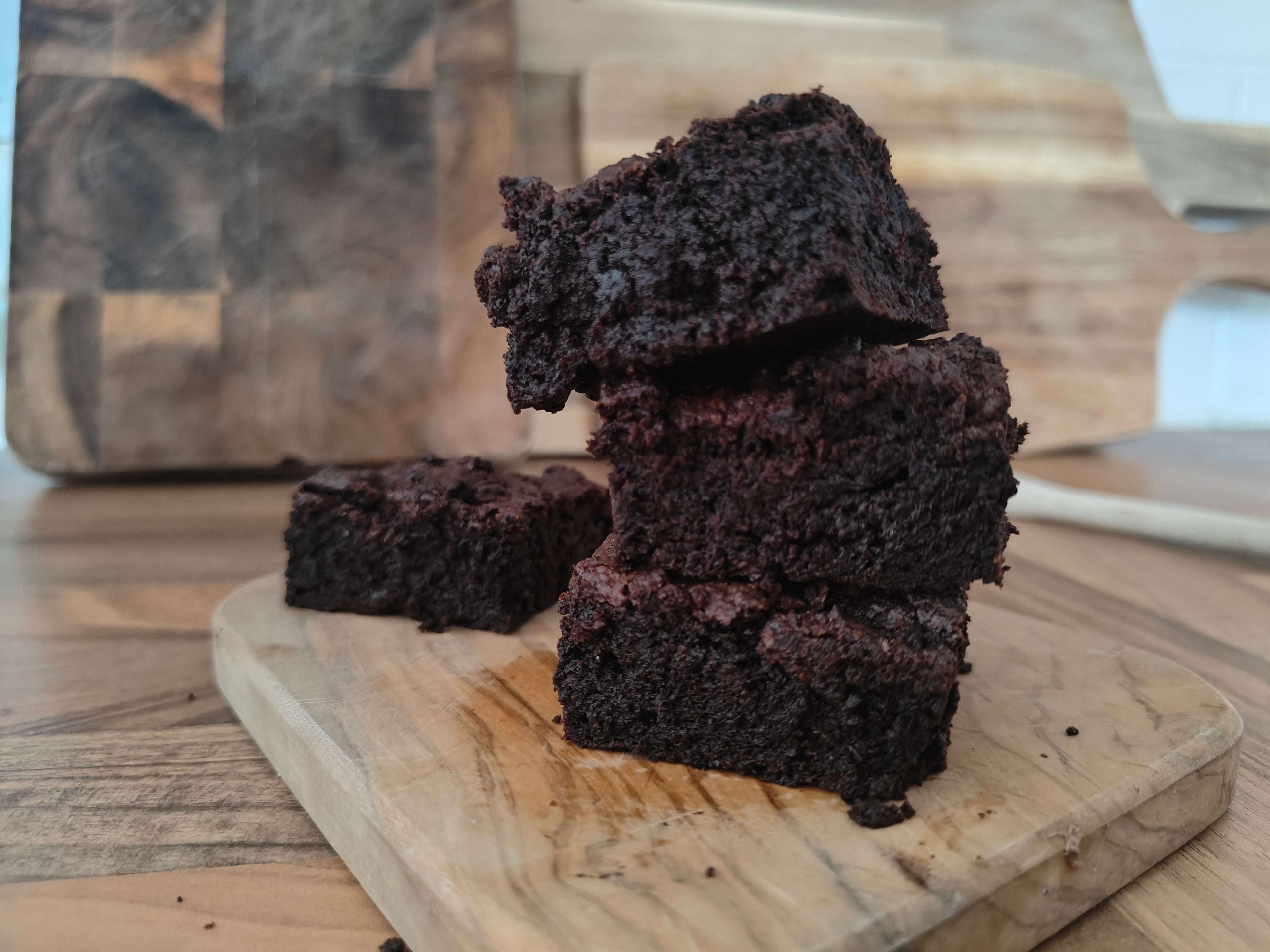 Stack of brownies on a wooden cutting board with a blurred background