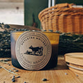 Candle with a label on a wooden surface with lavender and wicker baskets in the background