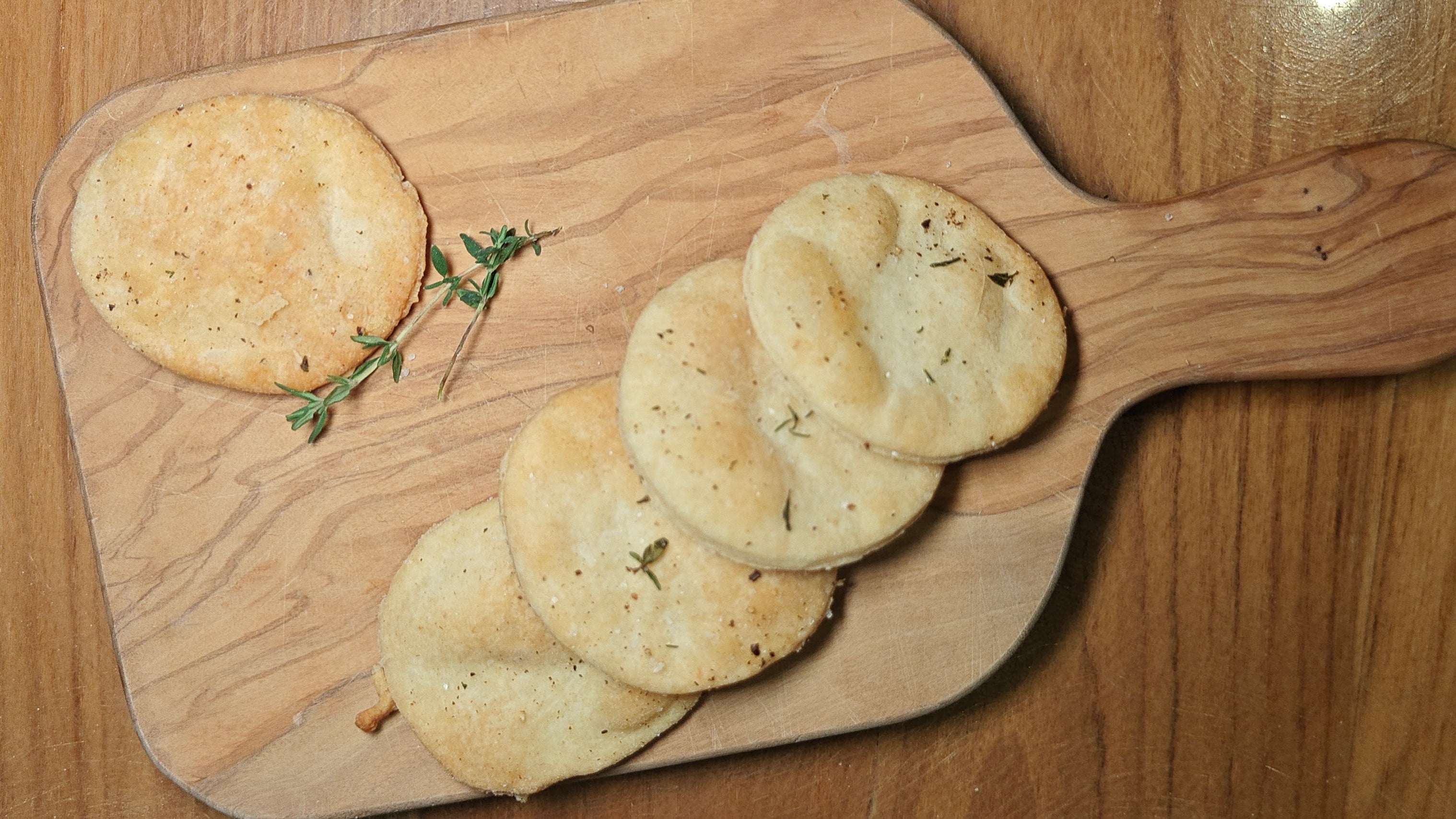 Wooden cutting board with round bread items on a wooden surface