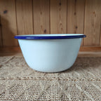 White enamel basin with blue rim on a textured surface with wooden background