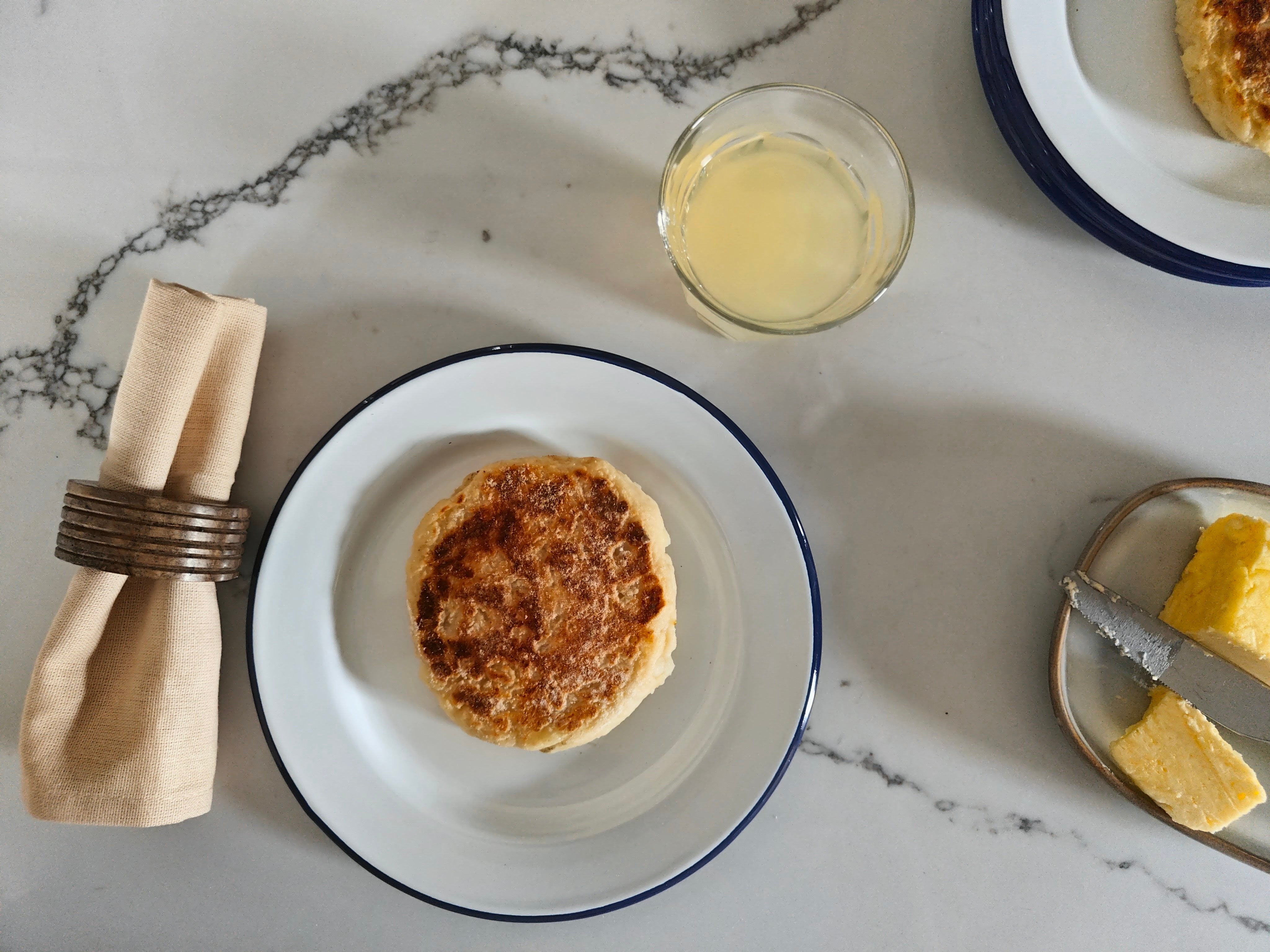 Traditional Potato Bread on a plate with a glass of juice and butter on a marble surface