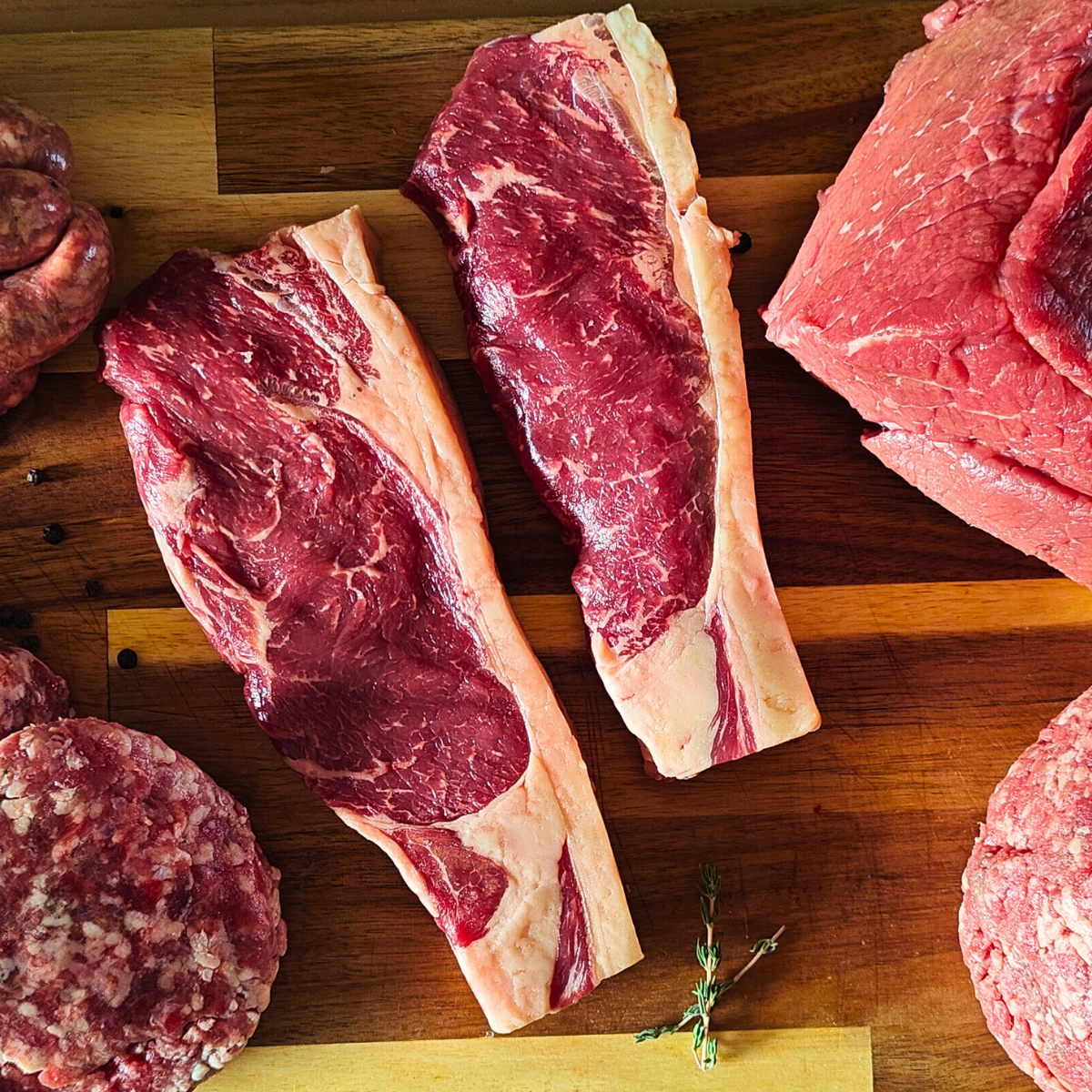 Assorted cuts of raw meat on a wooden cutting board