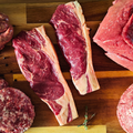 Assorted cuts of raw meat on a wooden cutting board