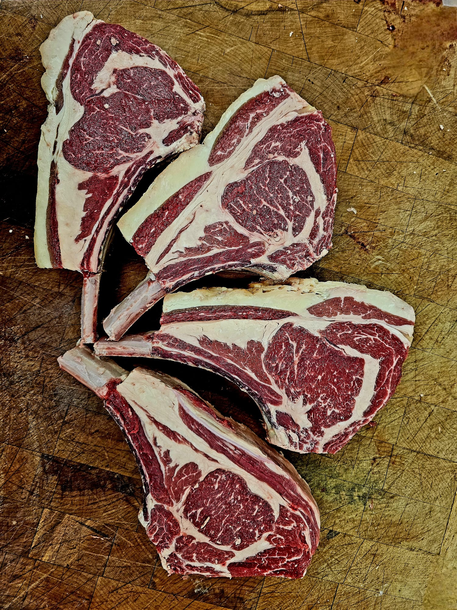 Raw tomahawk steaks on a wooden cutting board